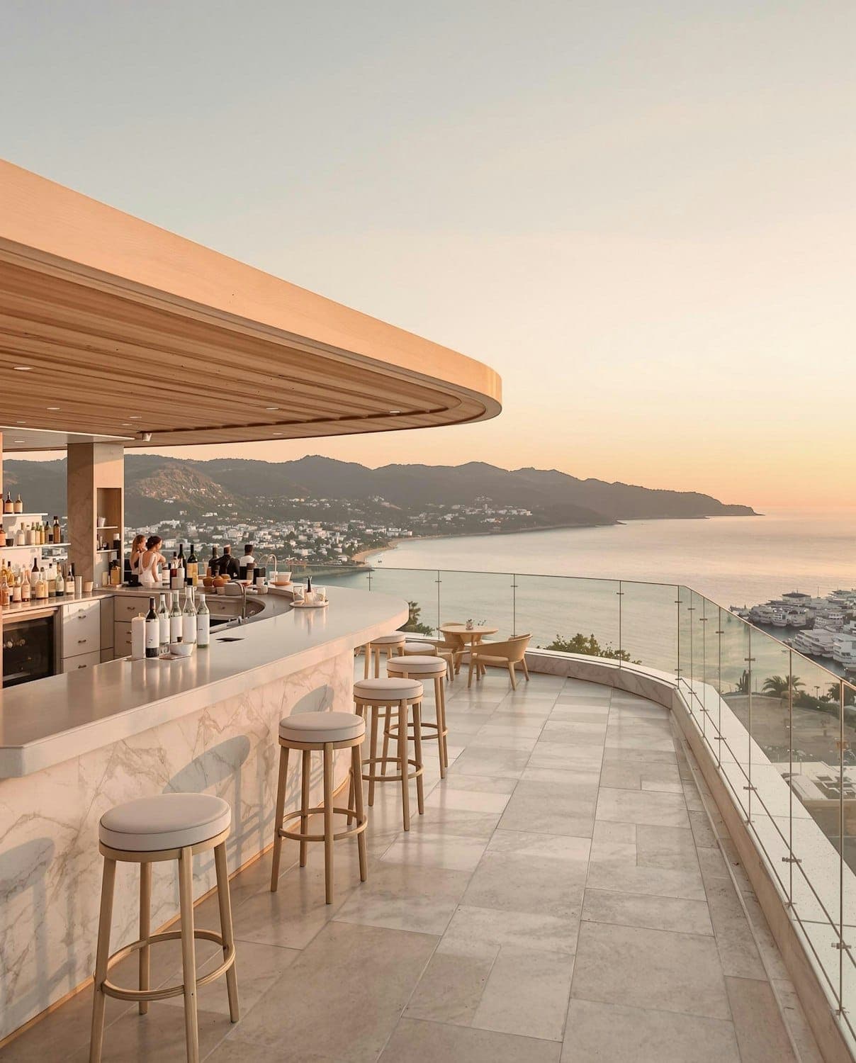 The upper terrace bar at sunset, a marble counter with timber stools facing the coast
