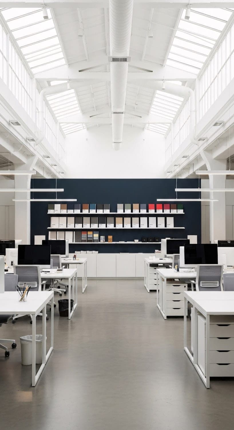 The studio: white desks under skylights, with a dark blue wall at the far end
